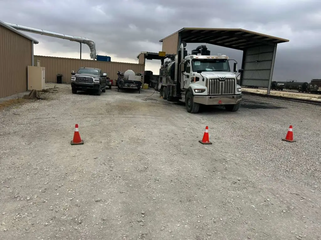 A Gentex hydrovac backed under a facility canopy for a clean-out, cones set out around the work area