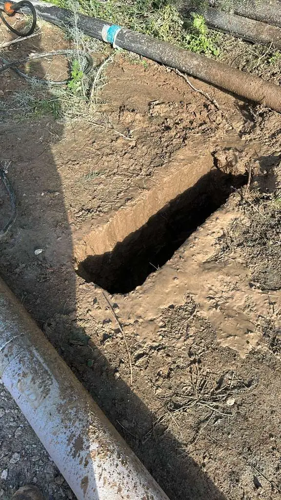 A hydro-excavated pothole opened straight down beside two buried lines, the walls cut clean and the lines left untouched