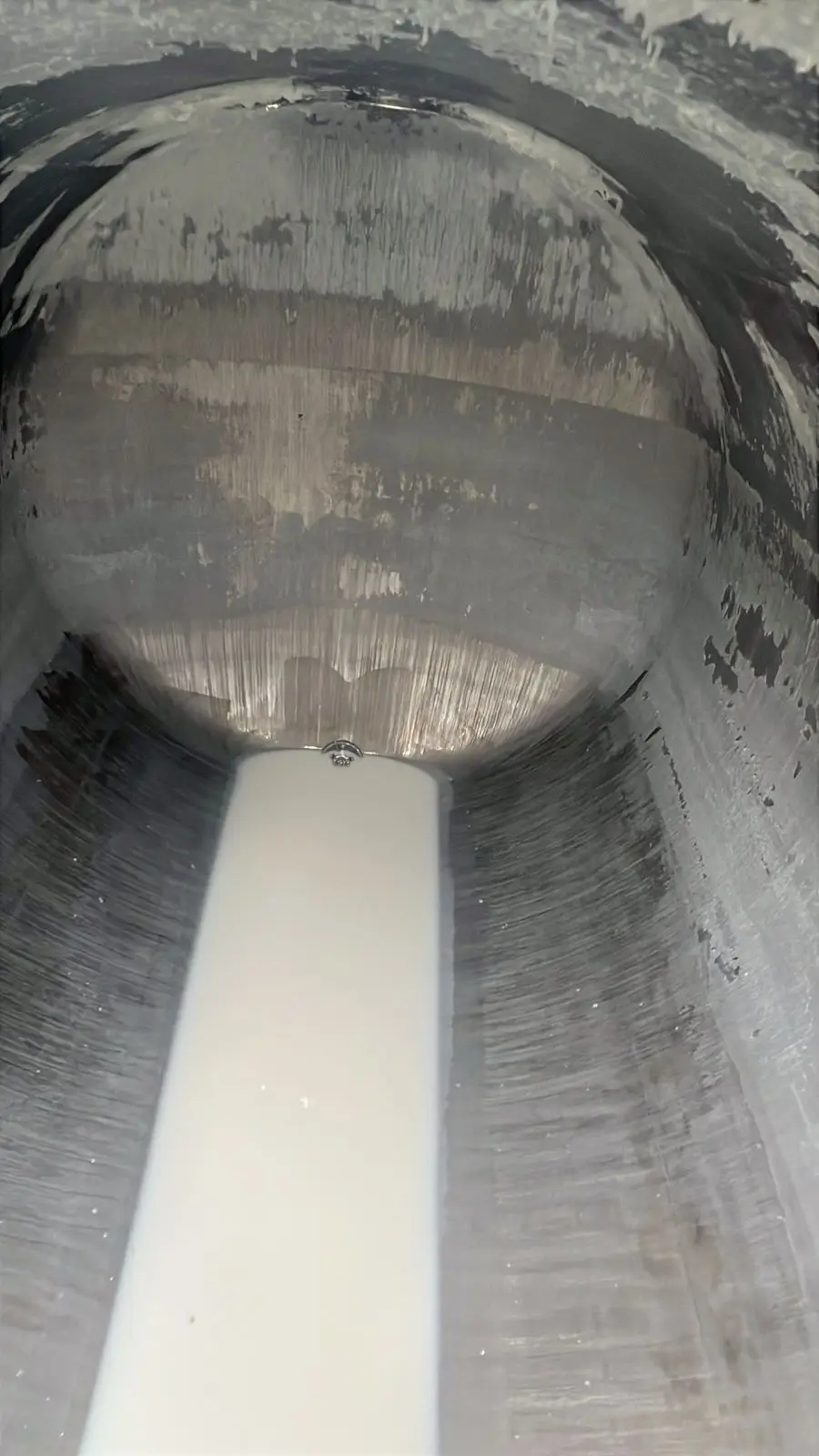 Inside a second ISO tank before cleaning: black product coating the shell and head from the top down