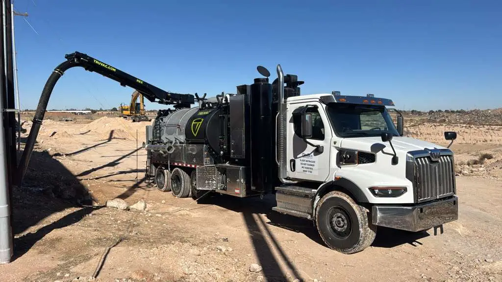 A Gentex hydro excavation truck working a dig, boom hose down in the hole and the vacuum pulling the spoil out